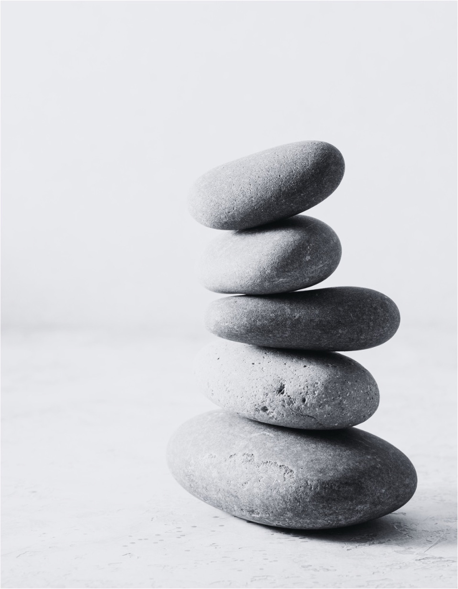 Five river stones balanced in a cairn — evenly weighted, quietly steady.